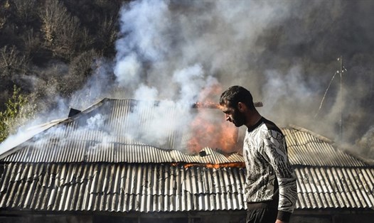Một người đàn ông đi ngang qua một ngôi nhà đang bốc cháy ở làng Charektar bên ngoài thị trấn Kalbajar trong bối cảnh xung đột quân sự giữa Armenia và Azerbaijan về khu vực Nagorno-Karabakh. Ảnh: AFP.