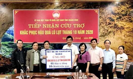 Phó Chủ tịch UBND tỉnh Long An - Phạm Văn Cảnh (thứ 5, phải qua) trao bảng tượng trưng tiền và quà hỗ trợ cho tỉnh Quảng Bình. K.N
