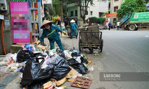 Công nhân Công ty Minh Quân dọn rác tồn đọng nhiều ngày trên phố Yên Phụ. Ảnh: Tùng Giang