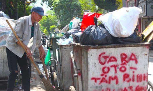 Công nhân vệ sinh môi trường Đỗ Văn Thơm bị zona thần kinh khá nặng nhưng vẫn cố gắng thu gom rác tại phố Chùa Láng (quận Đống Đa, TP.Hà Nội). Ảnh: Tú Quỳnh
