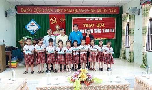 Ông Ngô Trọng Phi (áo xanh) - Phó Chủ tịch LĐLĐ huyện Phú Vang tặng vở cho các em học sinh sau mưa lũ. Ảnh: ĐP.