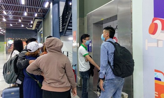 Hành khách chờ đợi trước thang máy trong nhà xe sân bay Tân Sơn Nhất để đón xe công nghệ.  Ảnh: Minh Quân