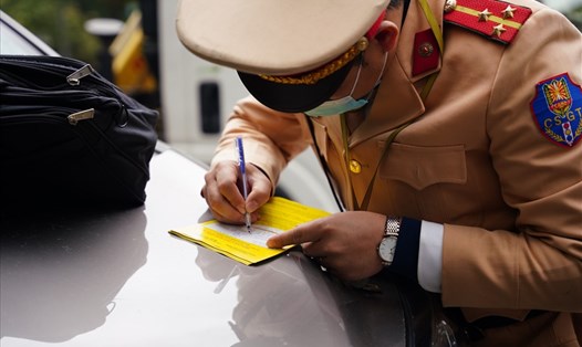 Cán bộ Đội Cảnh sát giao thông số 6 viết giấy phạt nguội với phương tiện dừng, đỗ trái quy định trong buổi ra quân hôm nay (15.12). Ảnh: V.Dũng.