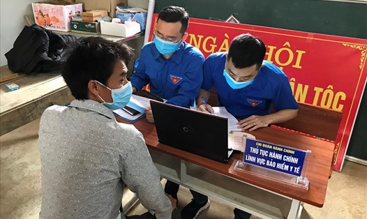 Cán bộ BHXH tỉnh Lào Cai hướng dẫn người dân hoàn thiện hồ sơ BHYT. 
Ảnh: BHLC