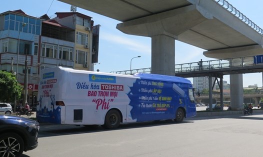 Một xe khách in kín mít quảng cáo xung quanh xe trên đường Hồ Tùng Mậu, Hà Nội. Ảnh: Phạm Đông
