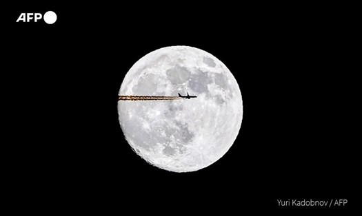 Bóng dáng chiếc máy bay bay ngang qua trăng rằm cuối cùng của năm 2020 ở Nga. Ảnh: AFP