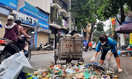 Công nhân môi trường đô thị căng mình thu gom rác trên phố Yên Phụ (quận Tây Hồ, Hà Nội). Ảnh: Anh Thư