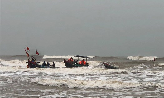 Lực lượng Biên phòng phối hợp với ngư dân cứu người và kéo thuyền cá bị chìm vào bờ. Ảnh: BP.