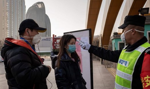 Bảo vệ kiểm tra nhiệt độ một phụ nữ ở lối vào công viên tại Bắc Kinh, Trung Quốc. Ảnh: AFP.