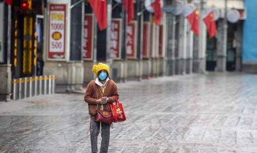 Một phụ nữ đeo khẩu trang đi trên đường phố thành phố Quảng Châu, tỉnh Quảng Đông, Trung Quốc. Quảng Châu là một trong 10 điểm nóng virus Corona tiềm tàng đang được WHO theo dõi chặt chẽ. Ảnh: EPA.