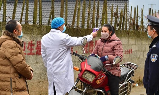 Nhân viên y tế đo thân nhiệt người dân tại ngôi làng thuộc khu tự trị dân tộc Choang ở Quảng Tây, Trung Quốc ngày 4.2. Ảnh: Tân Hoa Xã