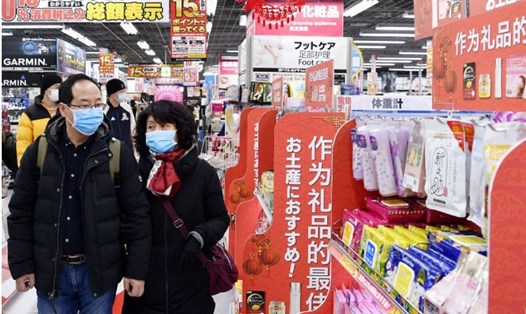 Du khách Trung Quốc đi qua 1 quầy bán khẩu trang trong một cửa hàng ở Nhật Bản. Ảnh: Kyodo.