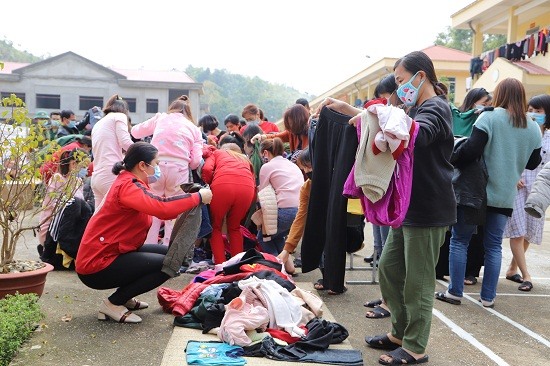 Công dân Việt Nam trở về từ Trung Quốc tại Khu vực cách lý Trung đoàn 852 (xã Ngũ Lão, huyện Hòa An) chọn quần áo ấm. Ảnh: Ngọc Anh