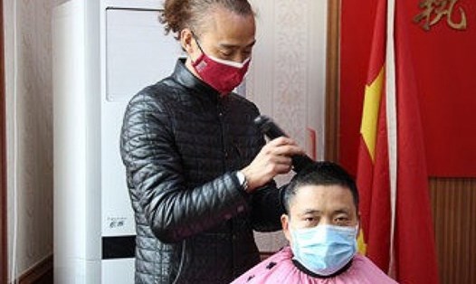Ông Đỗ Trạch Vũ cắt tóc cho 1 cảnh sát địa phương tại phòng họp sở cảnh sát. Ảnh: SCMP