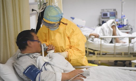 Bác sĩ giúp bệnh nhân COVID-19 uống nước trong phòng cách ly tại một bệnh viện ở Trung Quốc. Ảnh: Tân Hoa Xã.