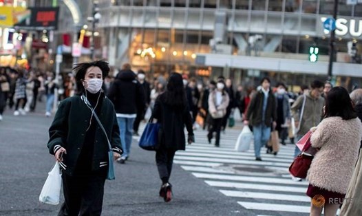 Một người phụ nữ đeo khẩu trang băng qua đường tại Shibuya ở Tokyo. Ảnh: Reuters.