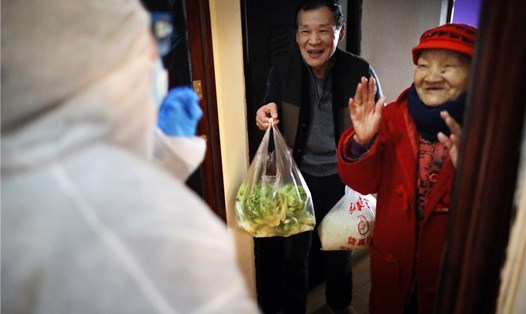Nhân viên cộng đồng kiểm tra, xác minh cư dân tại nhà và mang nguồn thực phẩm đến cho họ  ở quận Hán Dương, thành phố Vũ Hán, tỉnh Hồ Bắc vào ngày 21.2. Ảnh: China Daily