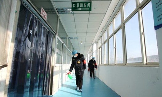Các tình nguyện viên cũng phun thuốc khử trùng ở các công ty sản xuất khẩu trang ở Trung Quốc. Ảnh: cnsphoto