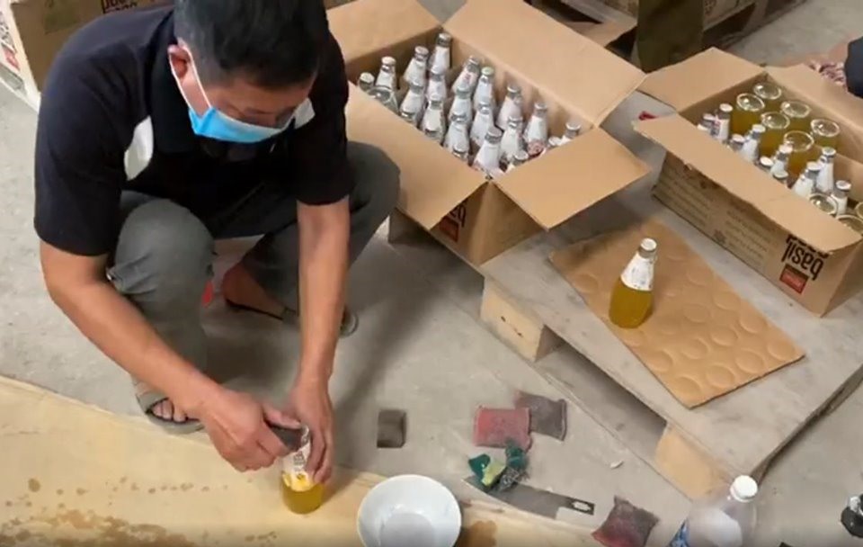 Các công nhân đang tẩy xóa ngày trên chai nước. Ảnh Anh Huy.