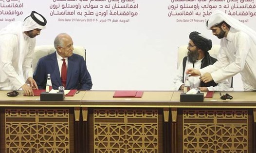 Đặc phái viên Mỹ Zalmay Khalilzad, và đại diện Taliban Mullah Abdul Ghani Baradar ký thỏa thuận tại Doha, Qatar. Ảnh: AP.