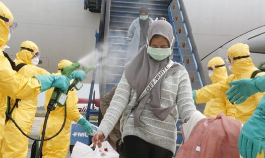 Hành khách sơ tán từ Vũ Hán trở về Indonesia được phun thuốc khử trùng khi bước xuống máy bay. Ảnh: Reuters.