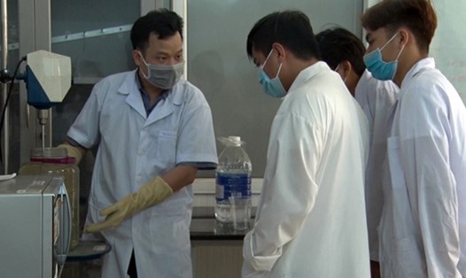 TS Đào Anh Quang - Trưởng Khoa Công nghệ Hóa - Môi trường cùng các cộng sự sinh viên điều chế nước rửa tay sát khuẩn phát cho người dân. Ảnh: DQT.