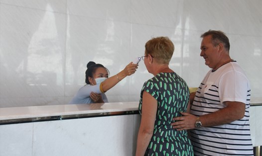Nhân viên lễ tân tại một khách sạn ở Nha Trang đo thân nhiệt cho du khách trước khi lưu trú. Ảnh: PV