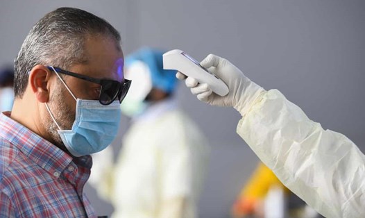 Quan chức y tế kiểm tra nhiệt độ cho một nam giới ở Kuwait hôm 12.3, một ngày sau khi WHO công bố COVID-19 là đại dịch. Ảnh: Anadolu/ Getty Images.