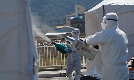 Các nhân viên trong trang phục bảo hộ đang khử trùng tại cơ sở kiểm tra COVID-19 ở quận Cheongdo, gần Daegu. Ảnh: Reuters.