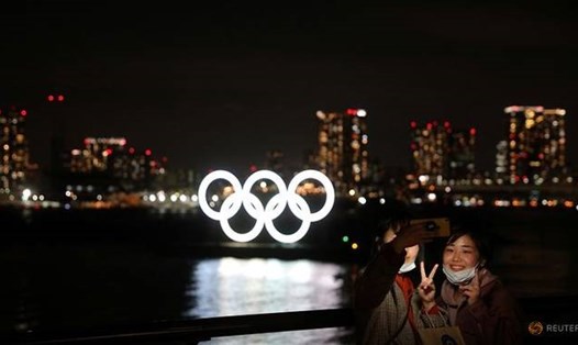 Du khách đeo khẩu trang chụp ảnh trước biểu tượng Olympic ở khu vực bờ sông tại Công viên hải dương Odaiba, Tokyo, Nhật Bản. Ảnh: Reuters