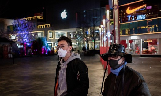 Hai người dân đeo khẩu trang đi bộ trước cửa hàng Apple ở Bắc Kinh, Trung Quốc. Ảnh: AFP