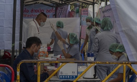 Bác sĩ đang kiểm tra nhiệt độ cho một người đàn ông tại bệnh viện dã chiến điều trị COVID-19 ở Bangkok. Ảnh: AP