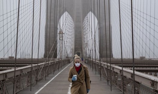 Một phụ nữ đeo khẩu trang đi bộ trên cầu Brooklyn tại thành phố New York. Ảnh: Getty.