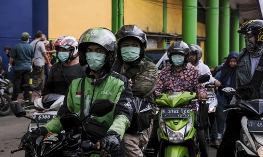 Những dân đeo khẩu trang bảo vệ khi đi xe máy bên ngoài một khu chợ ở Jakarta, Indonesia. Ảnh: The Star.