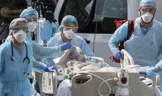 Nhân viên y tế trong trang phục bảo hộ hỗ trợ bệnh nhân. Ảnh: AFP.