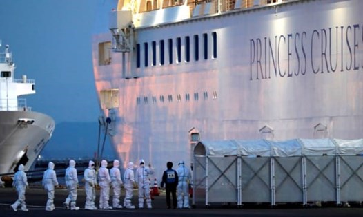 Nhân viên mặc đồ bảo vệ đi lên tàu du lịch Diamond Princess chuyển bệnh nhân COVID-19 tới bệnh viện. Ảnh: Reuters.