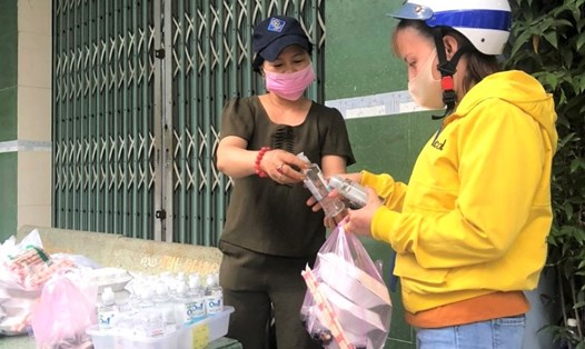 Bà Phù Nhật Phượng (bên trái) đang phát nước sát khuẩn và phần ăn chay cho công nhân ở trọ. Ảnh: Đức Long