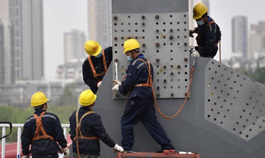 Công nhân xây dựng ở Vũ Hán đeo khẩu trang khi trở lại làm việc hồi tháng 3. Ảnh: Reuters.