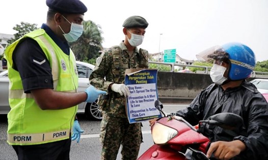 Cảnh sát Malaysia thông báo quy định phòng chống dịch COVID-19 cho một người dân lưu thông bằng xe máy tại trên đường phố ở Kuala Lumpur, Malaysia hôm 23.3. Ảnh: Reuters.