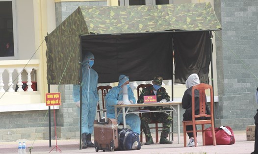 Nhân viên y tế làm thủ tục tiếp đón người từ vùng dịch về cách ly tại Trường Quân sự - Bộ Tư lệnh Thủ đô Hà Nội. Ảnh T.Vương