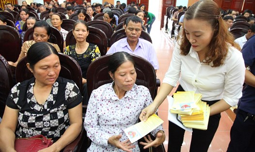 Nhân viên đại lý thu của Bảo hiểm xã hội (BHXH) tỉnh Ninh Bình phát tờ rơi tuyên truyền BHXH tự nguyện cho người dân. Ảnh: Nguyễn Trường