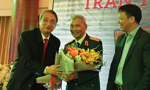 Thiếu tướng Nguyễn Đức Huy (giữa) nhận hoa chúc mừng trong ngày giới thiệu sách, sáng 5.3. Ảnh: VV