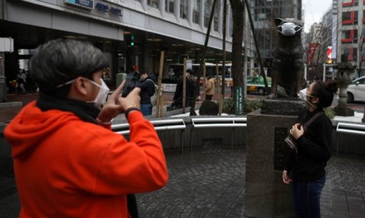 Người dân đeo khẩu trang chụp ảnh bên ngoài một nhà ga ở Nhật Bản. Ảnh: Reuters.