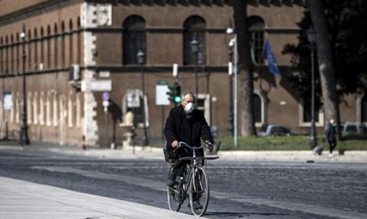 Một người đàn ông đeo khẩu trang đang đạp xe ở quảng trường Piazza Venezia, Rome, Italia trong đại dịch COVID-19. Ảnh: EPA-EFE
