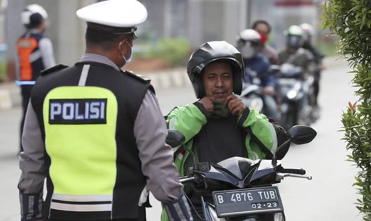 Cảnh sát yêu cầu một người lái xe máy đeo khẩu trang ở Jakarta, Indonesia. Ảnh: AP.