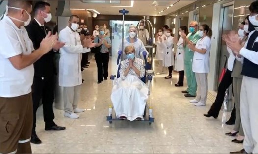 Cụ bà Gina Dal Colleto, 97 tuổi, đang được đẩy xe lăn rời khỏi bệnh viện Vila Nova Star ở Sao Paulo trong sự cổ vũ, vui mừng của các y bác sĩ, ngày 12.4. Ảnh: Reuters