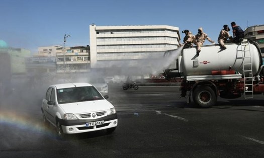 Một chiếc ô tô đi trên đường khi tình nguyện viên phun thuốc khử trùng tại quảng trường Enghelab ở Tehran, Iran hôm 3.4. Ảnh: Reuters.