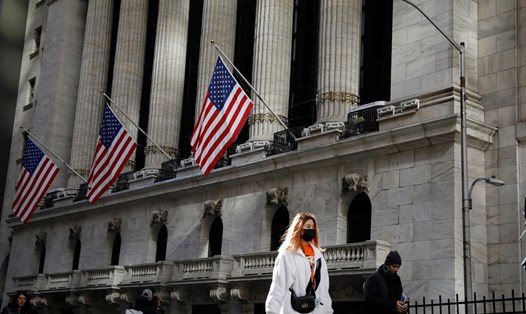 Một người phụ nữ đeo khẩu trang đi bộ gần sàn giao dịch chứng khoán New York. Ảnh Reuters/Brendan McDermid