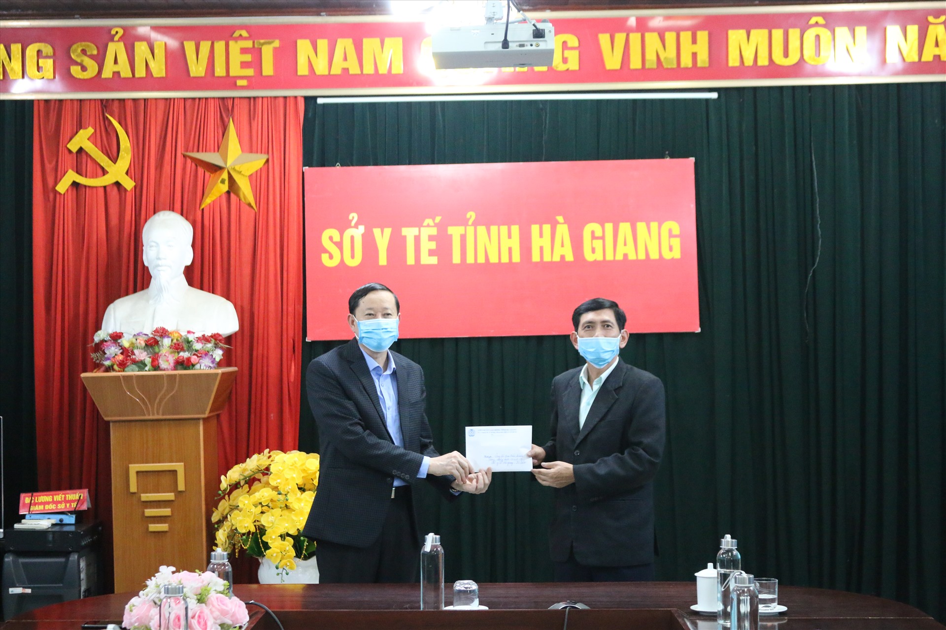 Đồng chí Nguyễn Văn Chung - Tỉnh ủy viên, Chủ tịch Liên đoàn Lao động tỉnh Hà Giang (bên phải) trao tiền ủng hộ tới Ban điều hành phòng, chống dịch COVID-19 Sở Y tế Hà Giang.