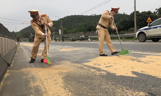 Cảnh sát giao thông Quảng Ninh tổ chức thu gom bột đậu tương trên đường QL 18A, giúp chủ xe tải  không may bị rơi vãi. Ảnh: Đỗ Giang
